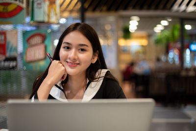 Portrait of a smiling young woman using phone