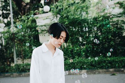 Young woman standing against trees