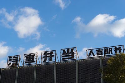 Low angle view of text on station against sky