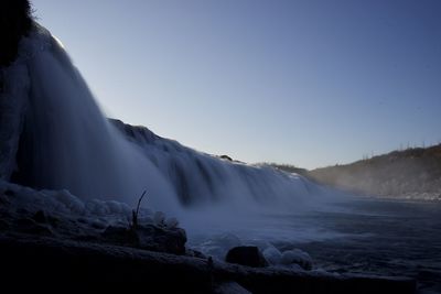 Scenic view of waterfall against clear sky