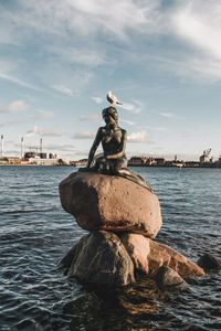 Statue by sea against sky