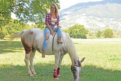 Full length of woman riding horse on field