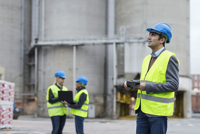 Male worker using digital tablet while looking away at factory