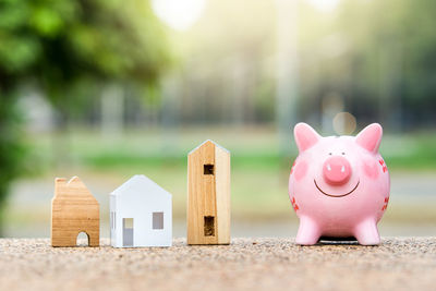 Close-up of piggy bank with model house outdoors