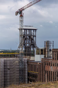 Crane at construction site against sky