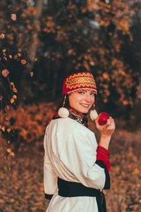 Portrait of smiling young woman wearing traditional clothing while standing in park during autumn