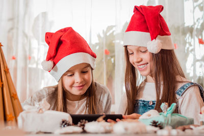 Girls in christmas decorations laugh and communicate with their families through a tablet.