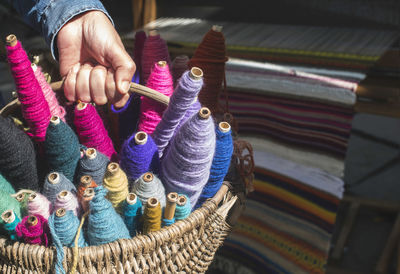 Cropped hands of person holding colorful wool in basket