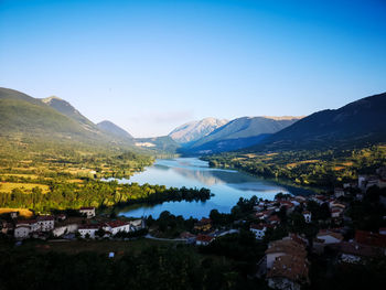 Scenic view of lake and mountains against clear blue sky