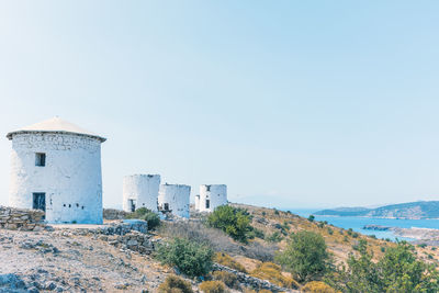 Buildings by sea against clear blue sky