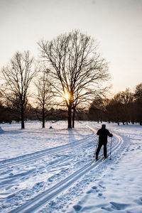 Rear view of man skiing on snow covered field against sky