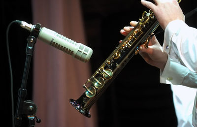 Cropped hands of male musician playing trumpet by microphone