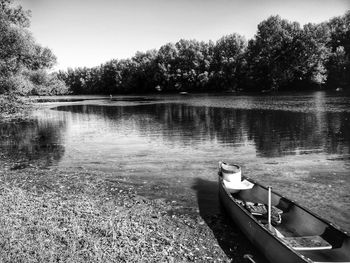 Boats moored in calm lake against trees