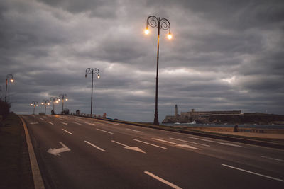 Street light on road against cloudy sky