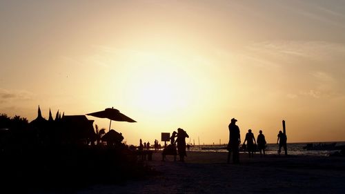 Silhouette people on beach against sky during sunset