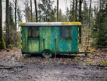 Abandoned cart on field against trees in forest