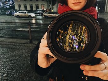 Midsection of woman holding camera while standing on street