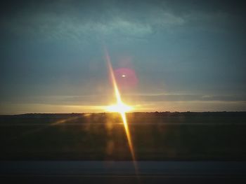 Sun shining through clouds over sea