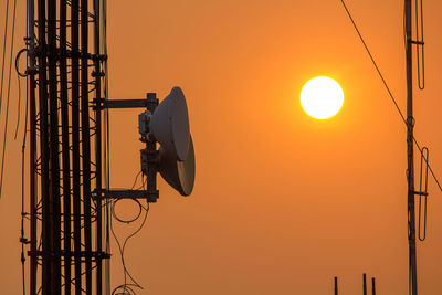 Low angle view of man working against orange sky