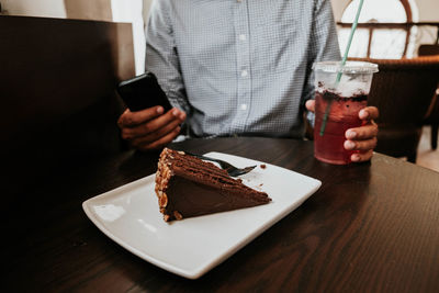 Midsection of man holding ice cream on table