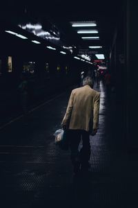 Rear view of man walking on at subway station 