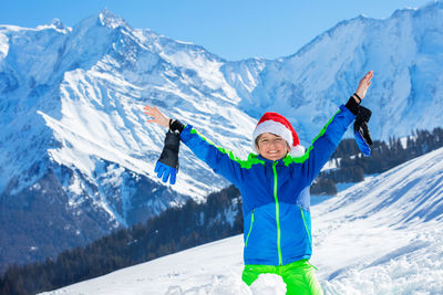 Portrait of smiling woman standing on snowcapped mountain
