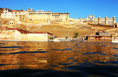 Amer fort by river against clear sky