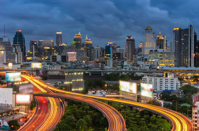 High angle view of light trails on road amidst buildings against sky