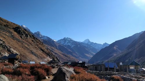 Panoramic view of houses and mountains against clear blue sky