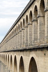 Low angle view of arch bridge against cloudy sky