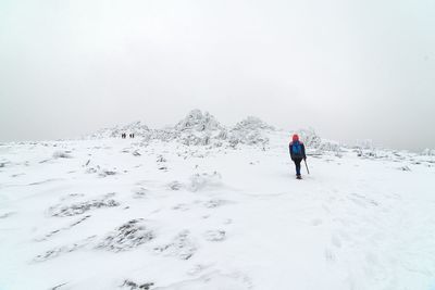 Rear view of person hiking on snowcapped mountain against sky