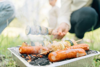 Midsection of man preparing food on barbecue grill