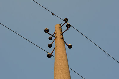 Low angle view of electricity pylon against clear sky