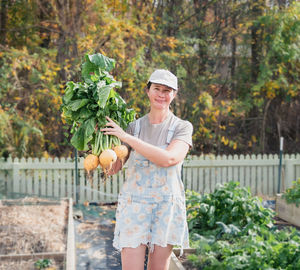 Portrait of smiling young woman standing by plants