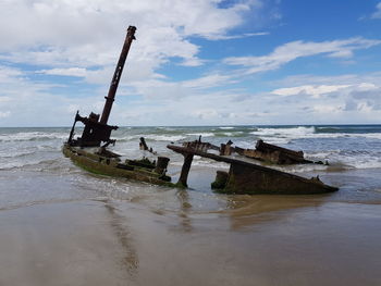 Abandoned boat on beach against sky