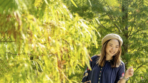 Portrait of smiling young woman standing against plants