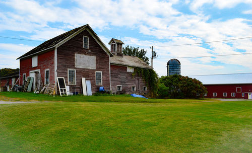 Houses on field by lawn against sky