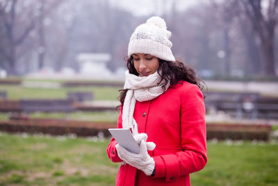 Full length of woman standing on mobile phone in winter