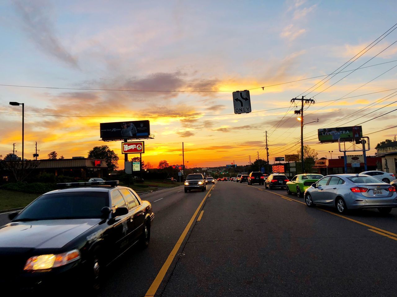 CARS ON ROAD AGAINST SKY DURING SUNSET