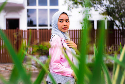 Portrait of woman standing against plants