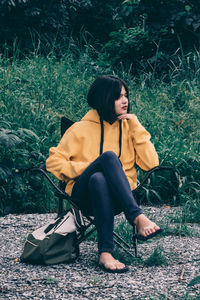 Young woman sitting on seat in field