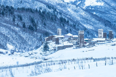 Snow covered buildings against mountain