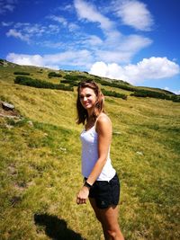 Full length of smiling young woman standing on field