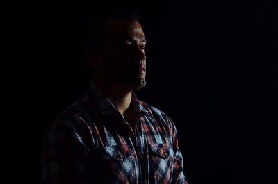 Portrait of young man against black background