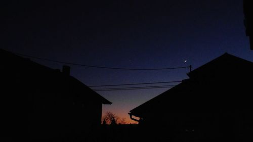 Low angle view of silhouette electricity pylon against sky at night