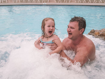 Cheerful father and daughter in swimming pool