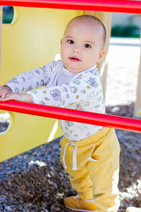 Cute happy smiling baby boy playing at children playground outdoors