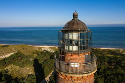 Aerial view at lighthouse of darß at baltic sea on island  with blue sky and the ocean in the back.