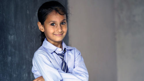 Portrait of young woman standing against wall
