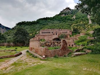 Old ruins on mountain against cloudy sky